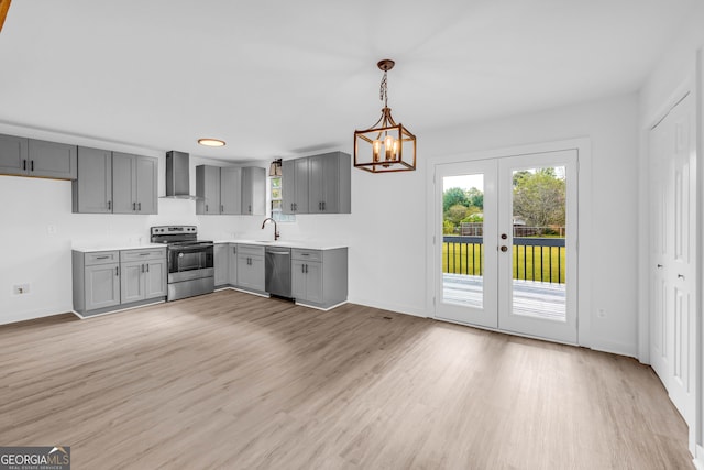 kitchen with decorative light fixtures, appliances with stainless steel finishes, wall chimney range hood, and gray cabinetry