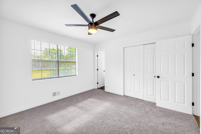 unfurnished bedroom featuring ceiling fan, a closet, and carpet flooring