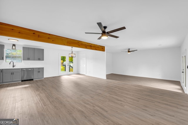 unfurnished living room featuring ceiling fan, beamed ceiling, hardwood / wood-style floors, and sink