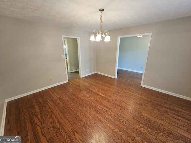 empty room with dark wood-style floors, a textured ceiling, and baseboards