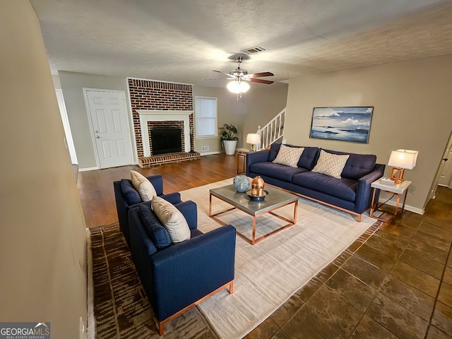 living room with visible vents, baseboards, stairs, a fireplace, and a textured ceiling