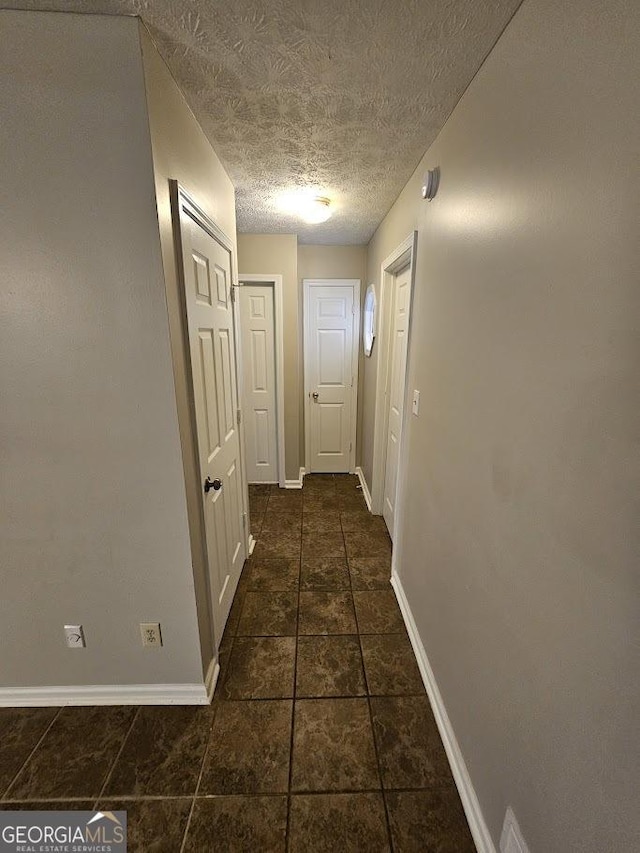 hall with baseboards and a textured ceiling