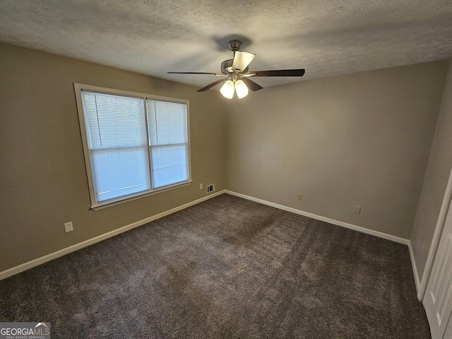 empty room featuring baseboards, a ceiling fan, dark carpet, and a textured ceiling