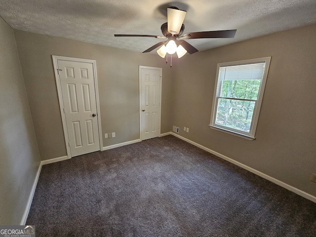 unfurnished bedroom featuring ceiling fan, baseboards, dark colored carpet, and a textured ceiling