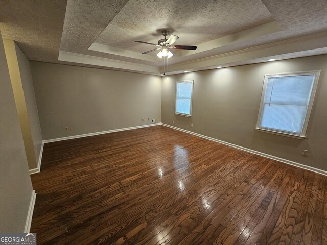 spare room featuring a tray ceiling, a textured ceiling, and wood finished floors