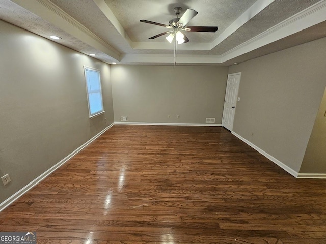 empty room featuring baseboards, visible vents, ceiling fan, dark wood-type flooring, and a raised ceiling