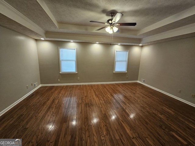 empty room featuring a raised ceiling, baseboards, and dark wood-style flooring