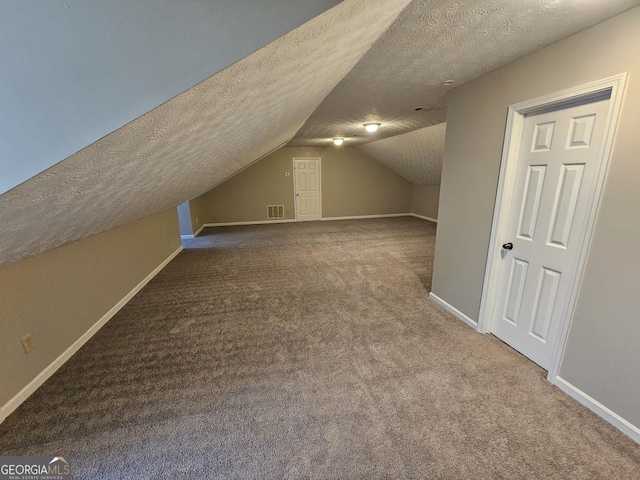 bonus room with lofted ceiling, visible vents, carpet floors, and a textured ceiling