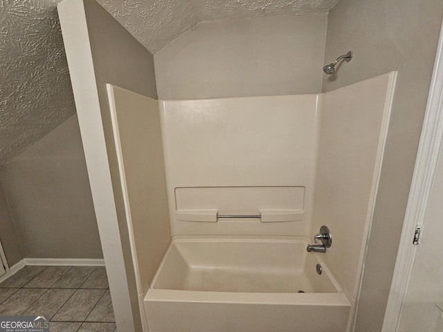 bathroom with lofted ceiling, a textured ceiling, tile patterned flooring, baseboards, and shower / bathtub combination