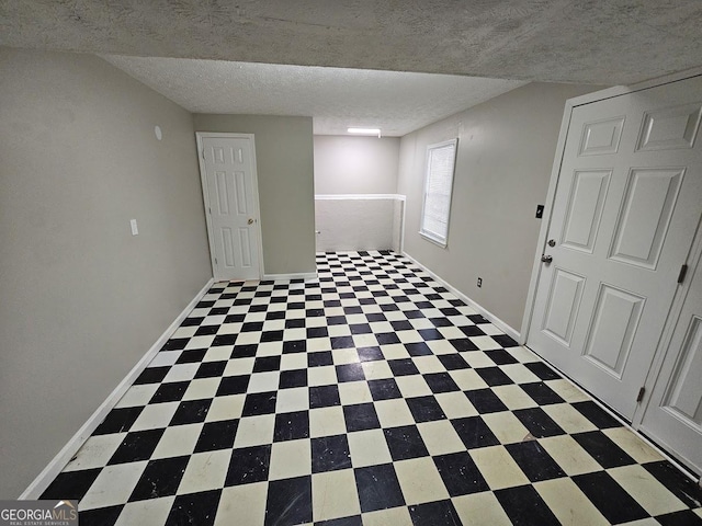 basement with tile patterned floors, baseboards, and a textured ceiling