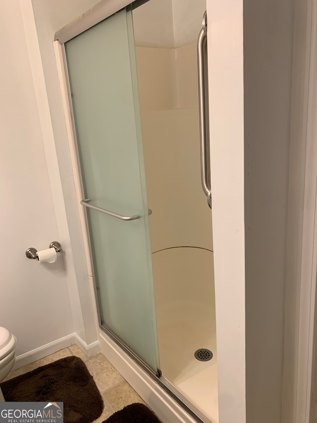 bathroom featuring a shower with shower door and toilet