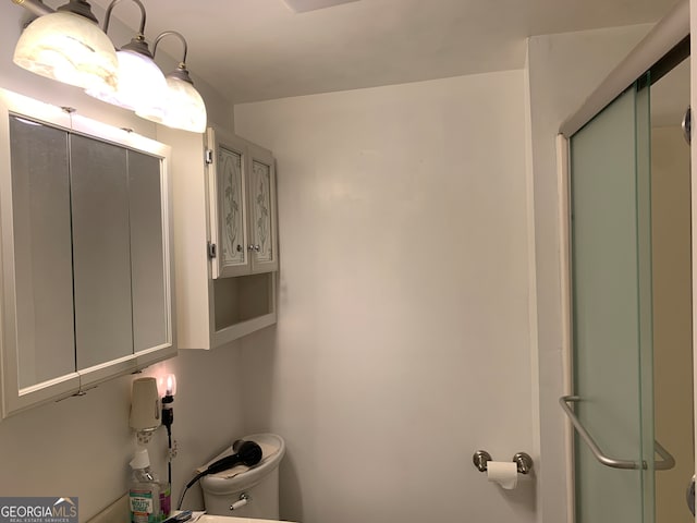 bathroom with a shower with shower door and toilet