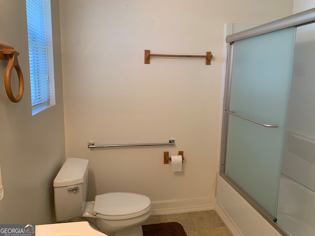 bathroom with tile patterned flooring, shower / bath combination with glass door, and toilet