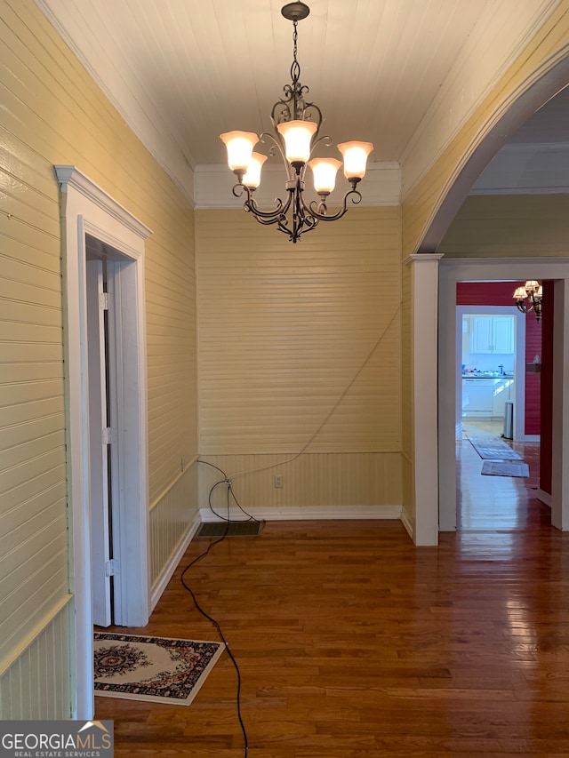 interior space featuring a notable chandelier, crown molding, and hardwood / wood-style flooring