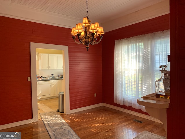 dining space with a notable chandelier, light wood-type flooring, and wooden walls