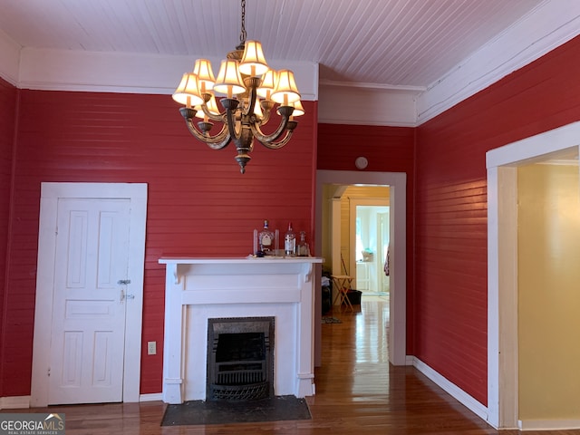 unfurnished living room with a notable chandelier, crown molding, wood walls, and hardwood / wood-style flooring