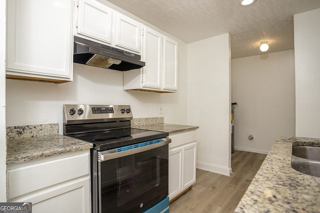 kitchen featuring light stone counters, stainless steel electric stove, light hardwood / wood-style floors, and white cabinetry