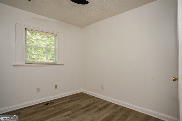 spare room featuring a textured ceiling and dark wood-type flooring