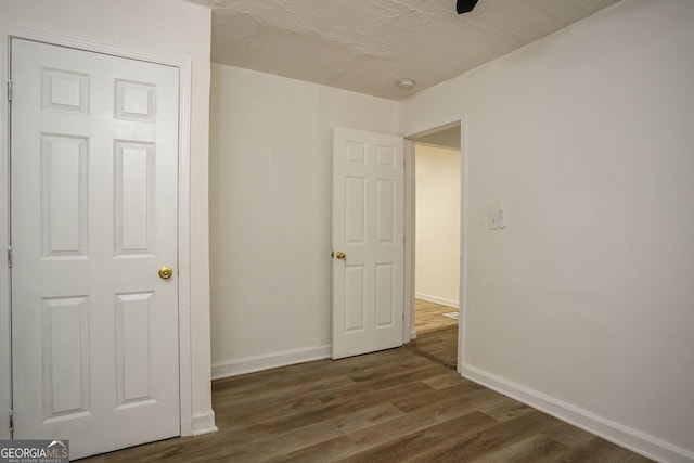 unfurnished bedroom featuring a textured ceiling and dark hardwood / wood-style floors