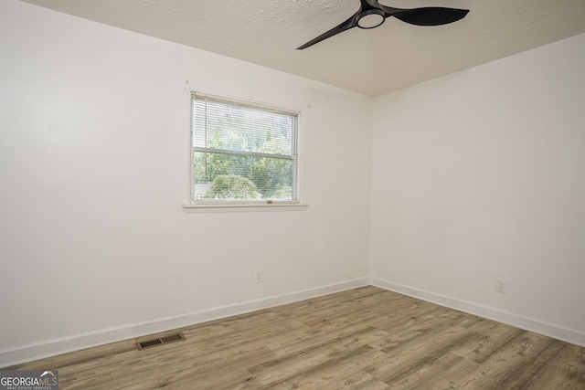 empty room with ceiling fan, hardwood / wood-style flooring, and a textured ceiling