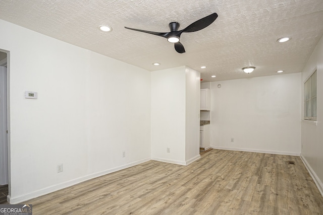 spare room featuring a textured ceiling, light hardwood / wood-style floors, and ceiling fan