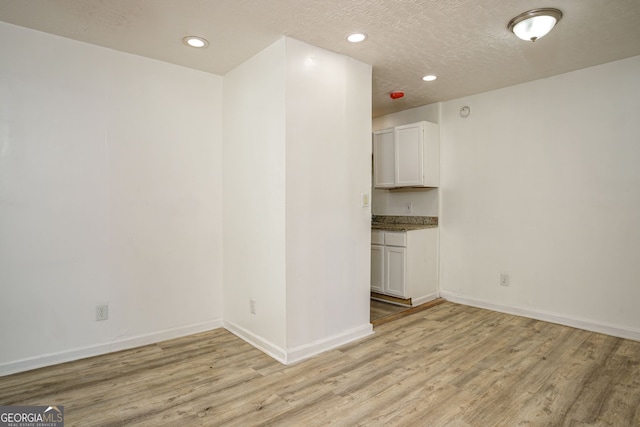 empty room featuring light wood-type flooring and a textured ceiling