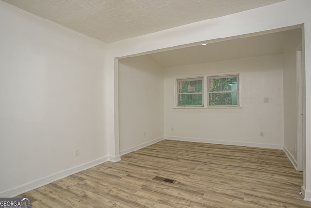 unfurnished room with light hardwood / wood-style flooring and a textured ceiling