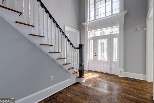 foyer entrance with a towering ceiling and dark hardwood / wood-style flooring