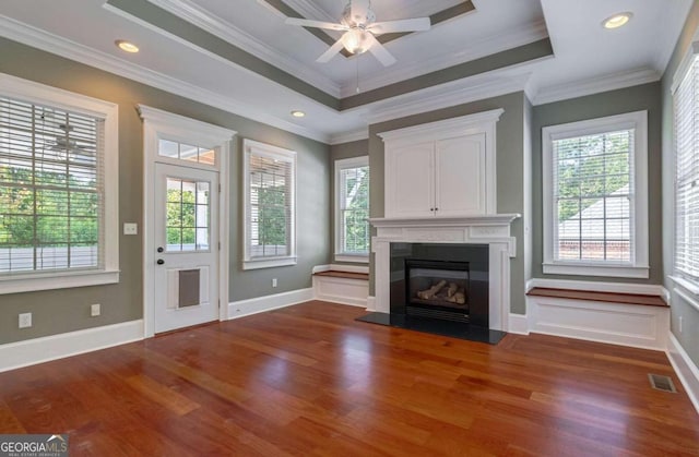 unfurnished living room with ornamental molding, a tray ceiling, ceiling fan, and dark wood-type flooring