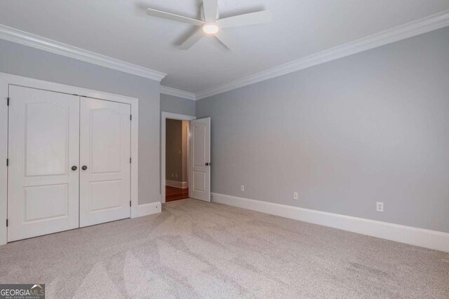 unfurnished bedroom with ceiling fan, a closet, crown molding, and light carpet