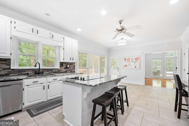 kitchen featuring white cabinets, a kitchen island, backsplash, stainless steel dishwasher, and stone counters