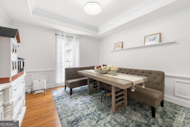 dining area with crown molding, a raised ceiling, and wood-type flooring