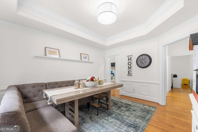 office with light hardwood / wood-style flooring, ornamental molding, and a tray ceiling