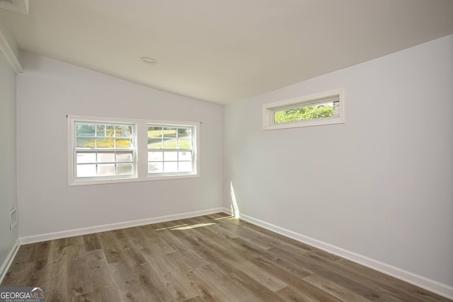 spare room featuring hardwood / wood-style floors and vaulted ceiling