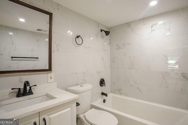 full bathroom with vanity, tile walls, tiled shower / bath combo, and toilet