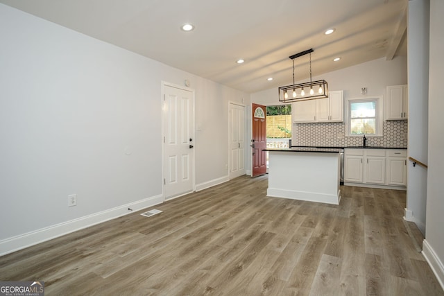 kitchen with vaulted ceiling with beams, decorative light fixtures, light wood-type flooring, and white cabinetry