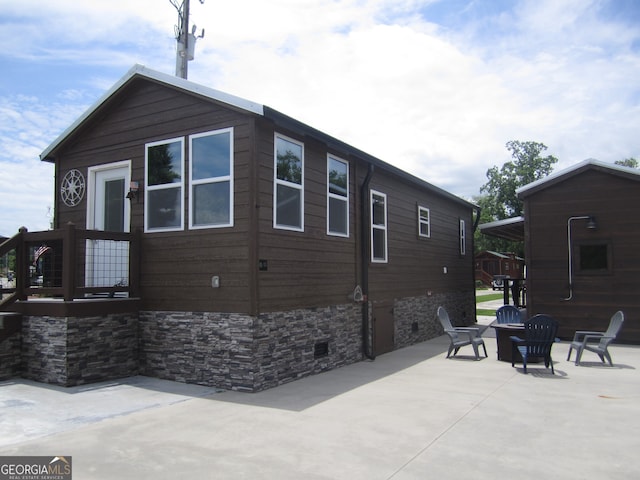 view of side of home with a fire pit, a storage unit, and a patio area