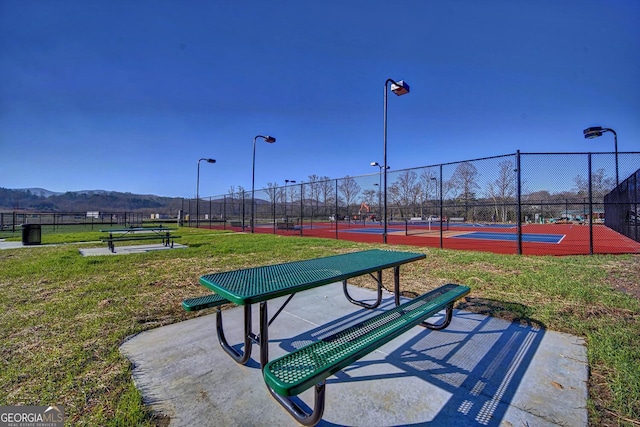 view of community with a mountain view, a yard, and tennis court