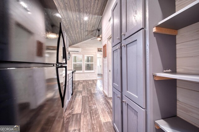 spacious closet featuring lofted ceiling, a wall unit AC, and hardwood / wood-style flooring