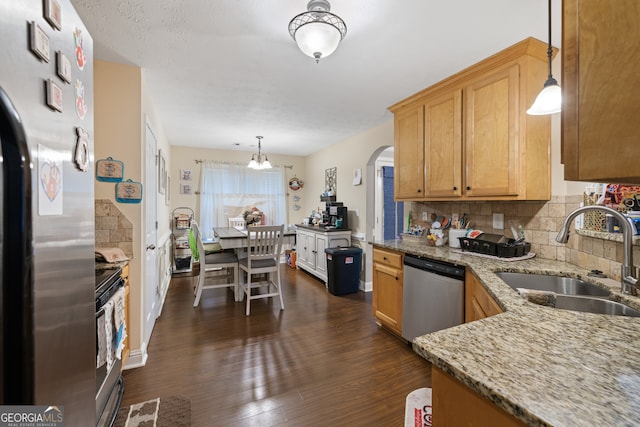 kitchen with sink, dark wood-type flooring, stainless steel appliances, and decorative light fixtures