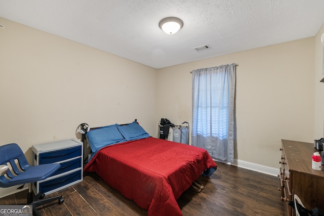 bedroom featuring a textured ceiling and dark hardwood / wood-style floors