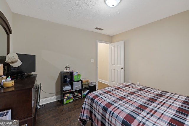 bedroom with a textured ceiling and dark wood-type flooring