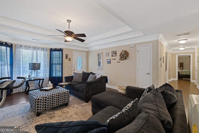 living room featuring ceiling fan, a raised ceiling, hardwood / wood-style floors, and crown molding