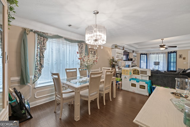 dining space with a healthy amount of sunlight, ceiling fan with notable chandelier, and dark hardwood / wood-style flooring