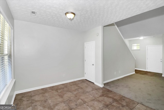 spare room with carpet floors and a textured ceiling