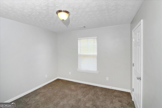 spare room with a textured ceiling and dark colored carpet