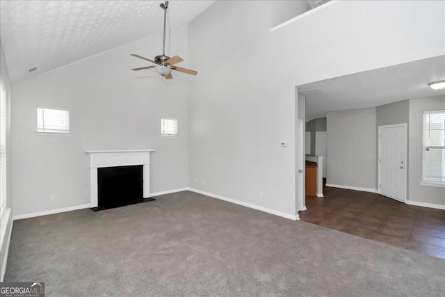 unfurnished living room with high vaulted ceiling, dark colored carpet, ceiling fan, and a textured ceiling