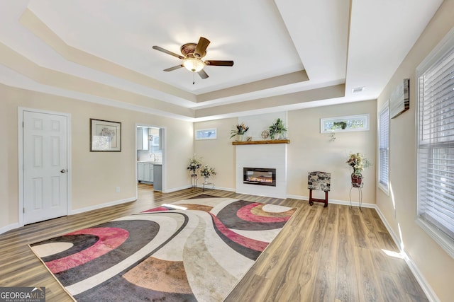 interior space featuring ceiling fan, sink, a tray ceiling, and hardwood / wood-style floors