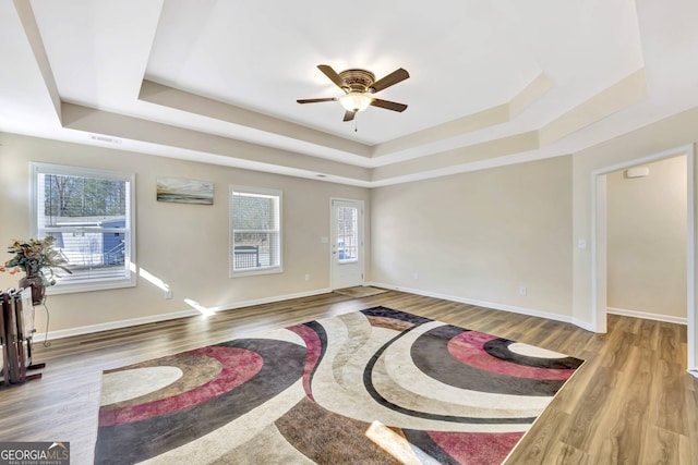 interior space featuring ceiling fan, hardwood / wood-style flooring, and a raised ceiling