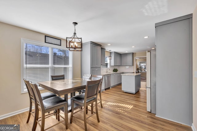 dining area with an inviting chandelier, light wood-type flooring, and sink